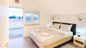 Un dormitorio con cama, mesita de noche y ventana.