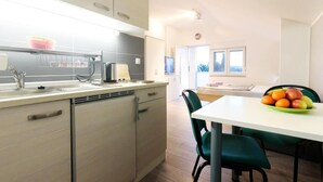Una cocina moderna con encimera blanca, un lavamanos y una zona de comedor con mesa y sillas.