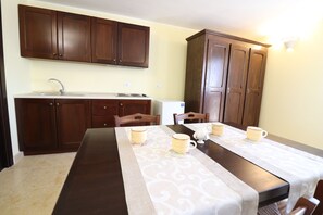 A kitchen with wooden cabinets, a sink, and a dining table with a tablecloth. - B b With Swimming Pool Tenuta Agrumi del Salento Triple Deluxe Citrus Attic (Carmiano)