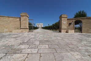 Une cour dallée, bordée de murs en pierre et dotée d’une entrée en arc de cercle.