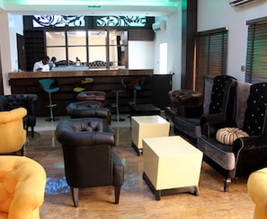 A bar area with stools, a counter, and a seating area with sofas and armchairs.