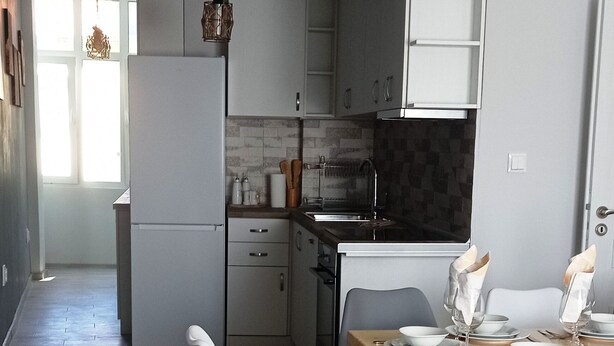 Una cocina moderna con armarios blancos, una mesa de comedor de madera con sillas, y una lámpara colgante.