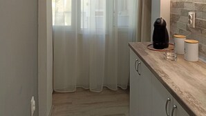 Una cocina moderna con armarios de colores claros, una cafetera y un vaso sobre la encimera.