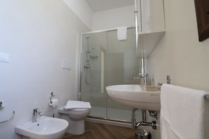 A modern bathroom with a glass-enclosed shower, a sink, and a toilet. - Comfort Lime Double (Carmiano)