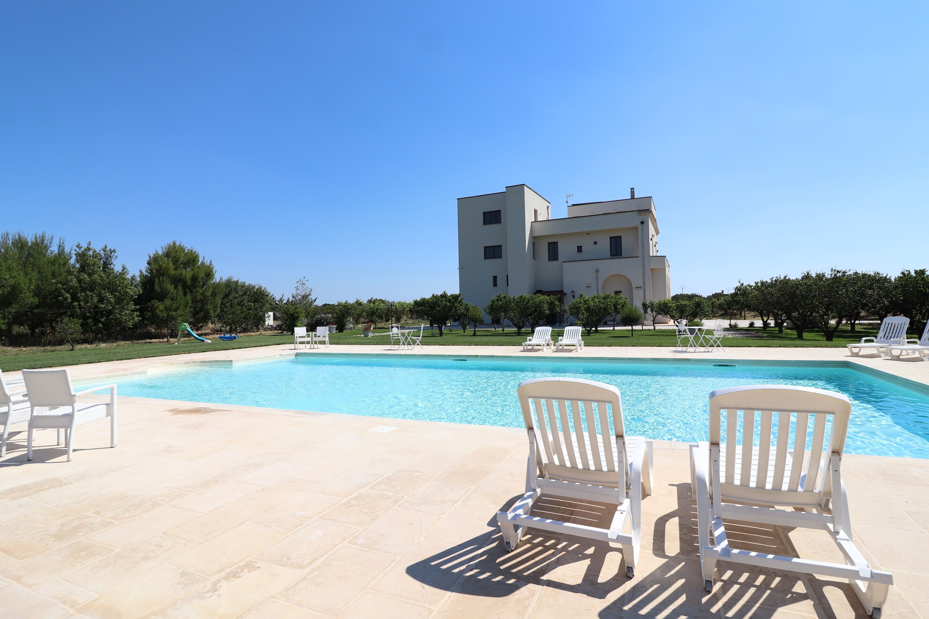 A swimming pool with lounge chairs and a building in the background.