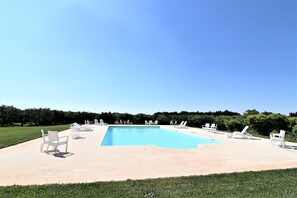 A rectangular swimming pool with a tiled deck, surrounded by white lounge chairs. - Matrimoniale Delux Washinton (Carmiano)