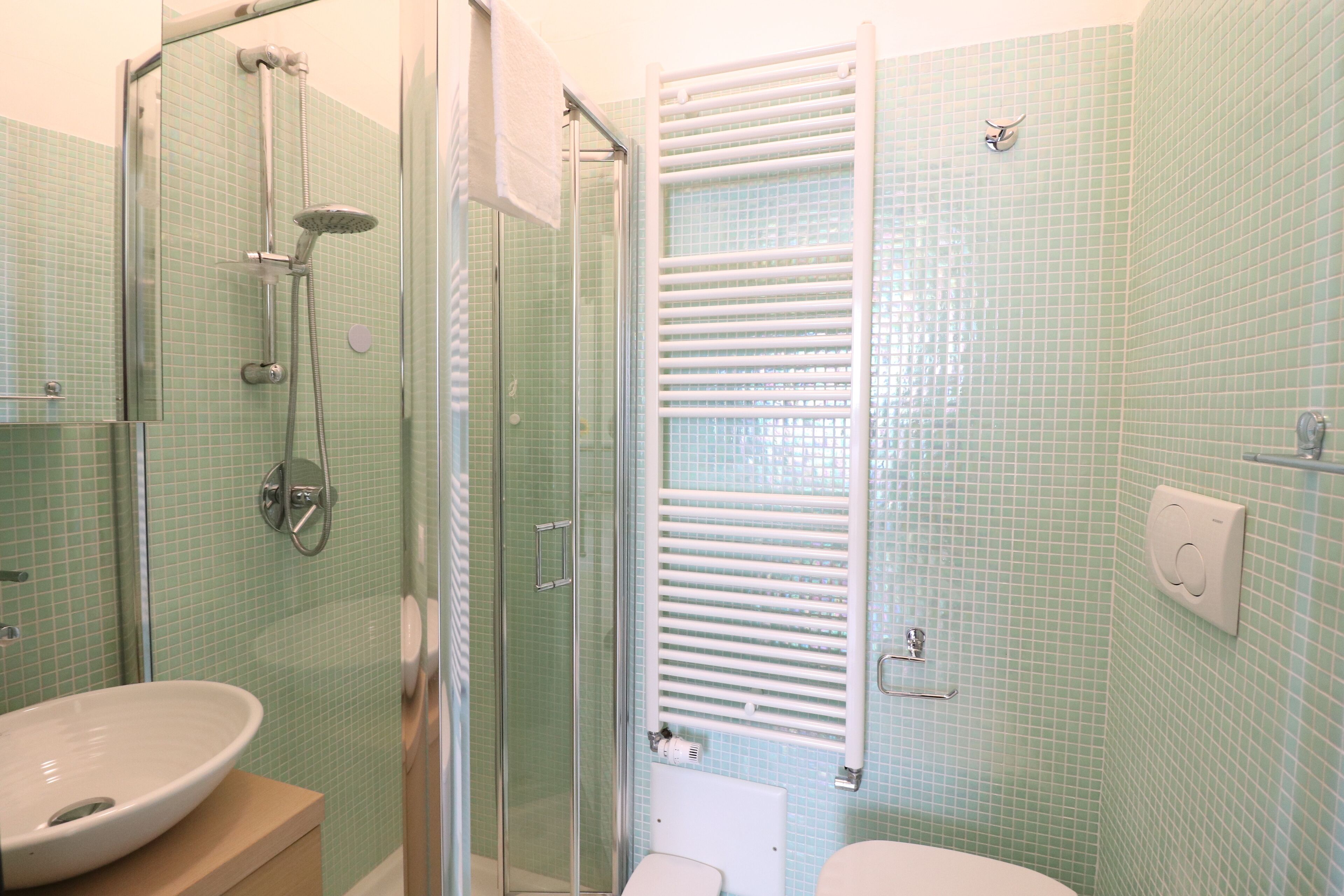 A bathroom with a glass-enclosed shower, a sink, and a toilet.
