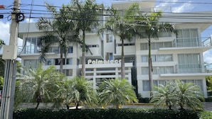 A multi-story building with balconies, palm trees, and a sign reading "Palmares." - Peace In The Village, Punta Cana Village (Punta Cana)