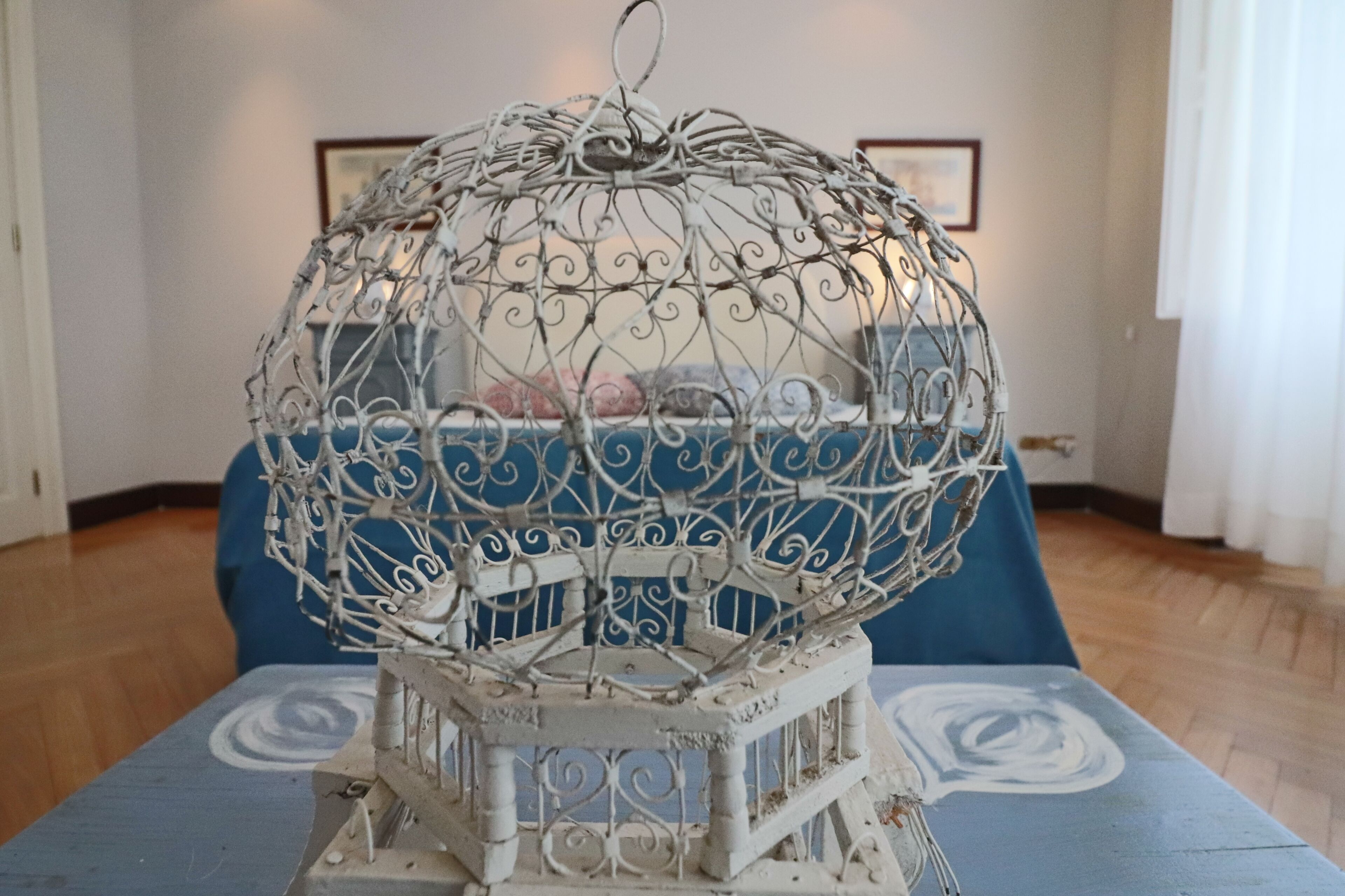 A metal birdcage with intricate designs on a table.