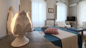 A room with a bed, a table with a lamp, a television, and a chair. - Relais Delle Rose - Mimmi Executive Suite (Lecce)