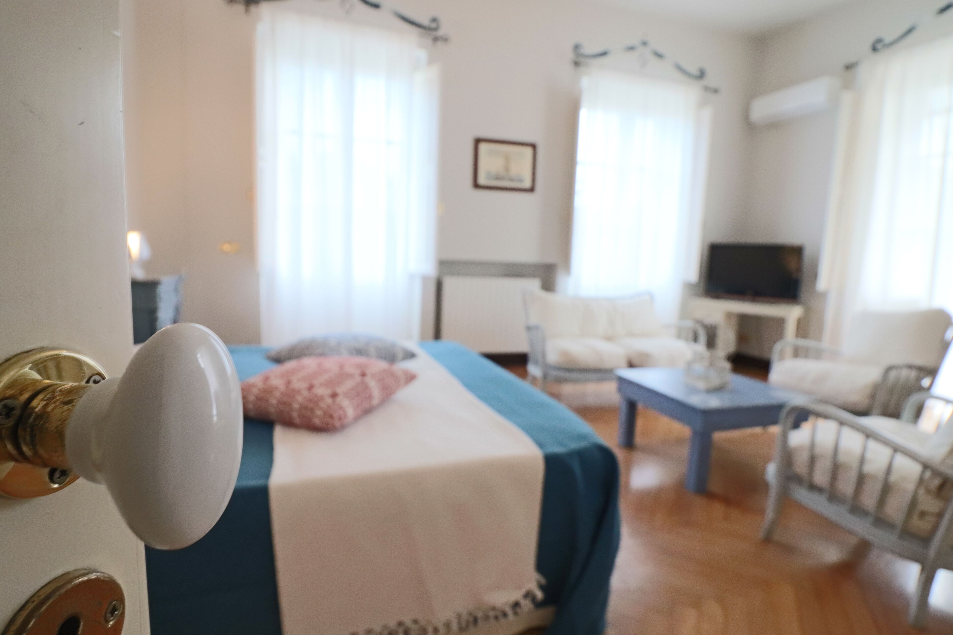 Una stanza con un letto, una televisione e una poltrona.