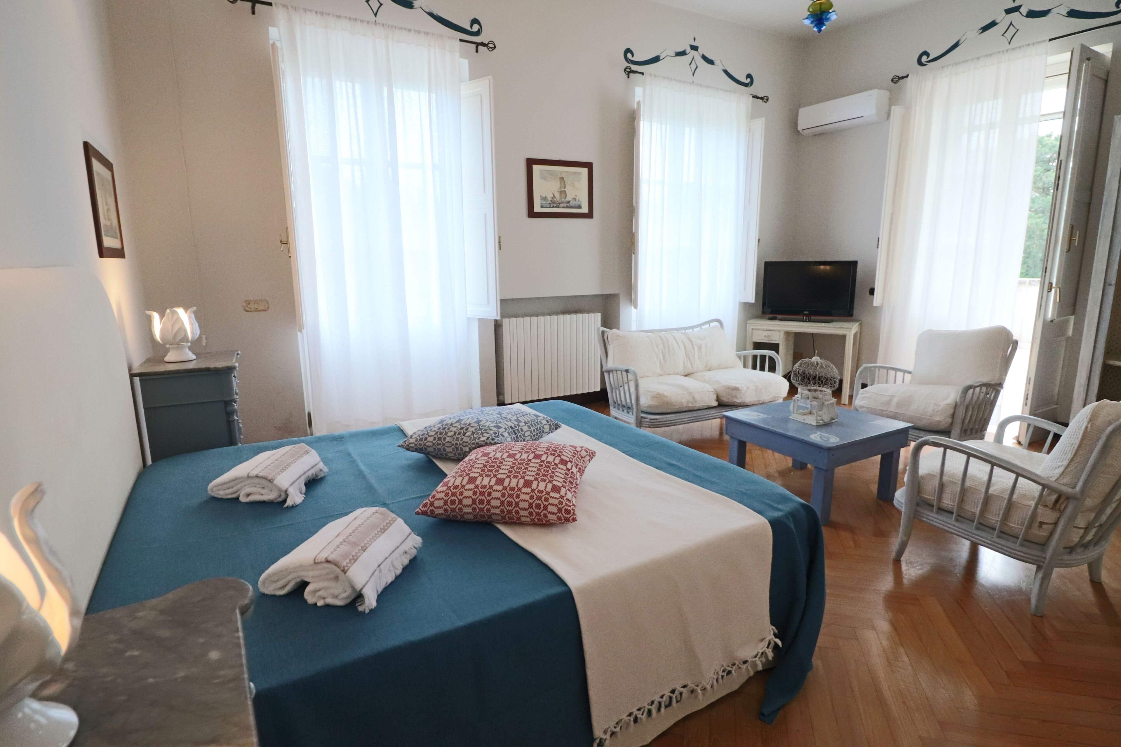 A hotel room with a bed, a small table, a TV, a chair, and a radiator.