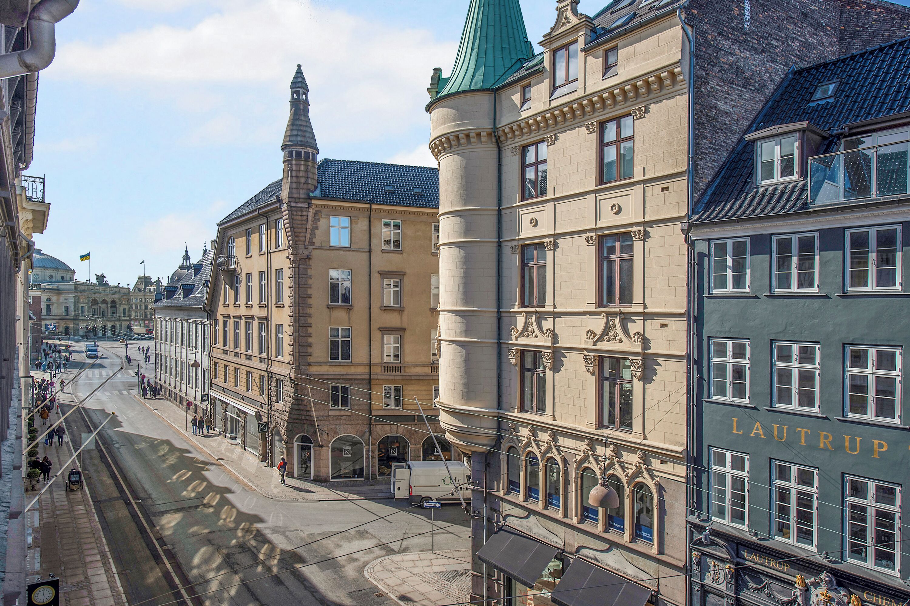 A street view with historic buildings, including a building with 'LAUTRUP' signage.
