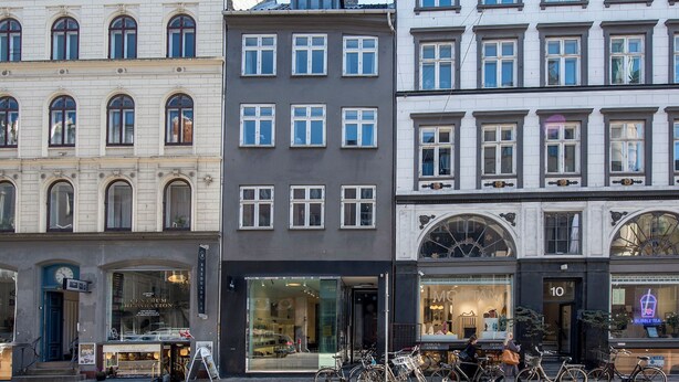 Een rij gebouwen met etalages, waaronder een bubble tea winkel en een zaak met een groot glazen raam.