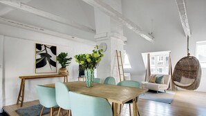 Een eetgedeelte met een houten tafel, teal stoelen en een bloemenvaas.