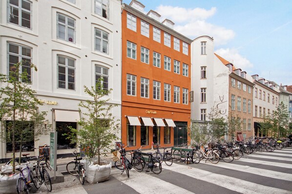 A row of bicycles parked along a street with buildings in the background.