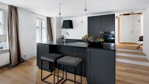 A modern kitchen with a central island, dark cabinetry, and pendant lighting. - Regent 7 - Large 3 Bdr Apt With Balcony in City Centre (Copenhagen)