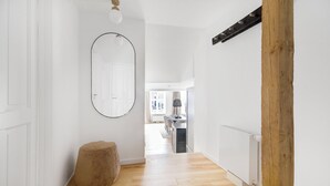 A hallway with a wooden floor, a round mirror, a small stool, and a radiator. - Regent 7 - Large 3 Bdr Apt With Balcony in City Centre (Copenhagen)