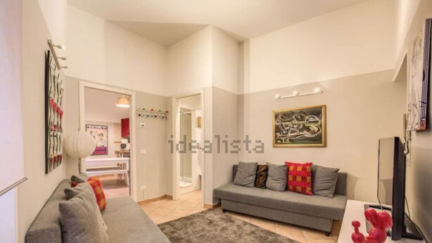 A modern living room with a grey sofa, a coffee table, and a flat-screen TV. There is a painting on the wall and a red sculpture on the coffee table. - Campo dei Fiori, Lovely Apartment "easy Life In Rome" (Rome)