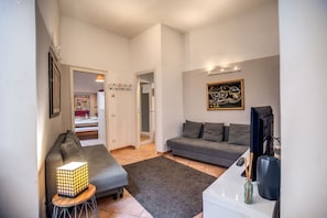 A modern living room with two grey sofas, a coffee table, a TV, and a lamp.