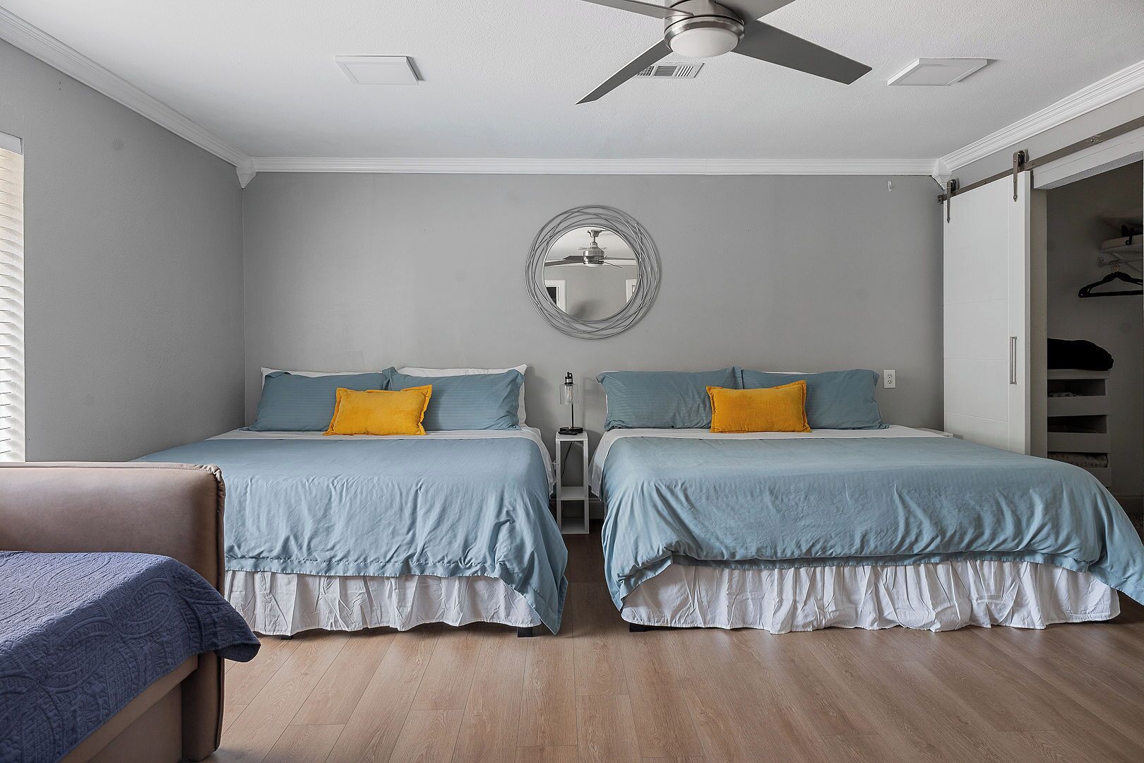 Une chambre avec deux lits, un ventilateur de plafond, un miroir et un dressing.
