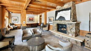 A spacious living area with a stone fireplace, leather furniture, and framed artwork on the walls.