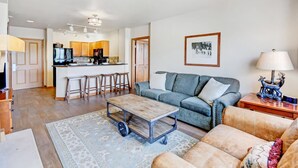 A modern living room with a grey sofa, a wooden coffee table, and a patterned rug.