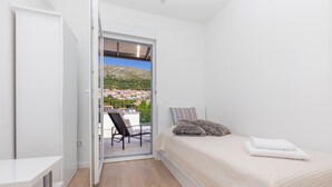 Ein Schlafzimmer mit einem Bett, einem Sessel und Blick auf eine Stadt durch eine Glastür.