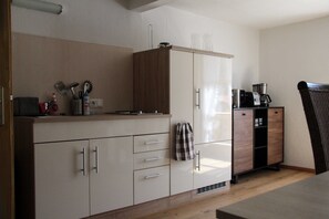 Una cocina con armarios, cafetera y una silla.