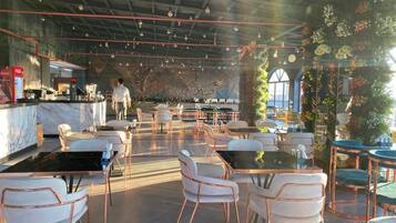 Een ruim restaurant met hoge plafonds, zichtbare balken en diverse zithoeken, waaronder tafels met stoelen.