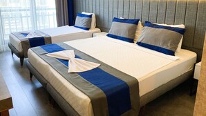 Habitación de hotel con dos camas, cada una con colcha azul y blanca, y cabeceros tapizados grises.
