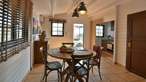 Un comedor con mesa y sillas de madera, una cesta de fruta y vistas al exterior.