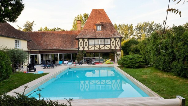 A traditional Tudor-style house with a swimming pool in the backyard.