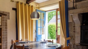 A dining area with a round table set for four, a blue and white patterned tablecloth, and wooden chairs. - Gîte du Château de Montafilan (Corseul)