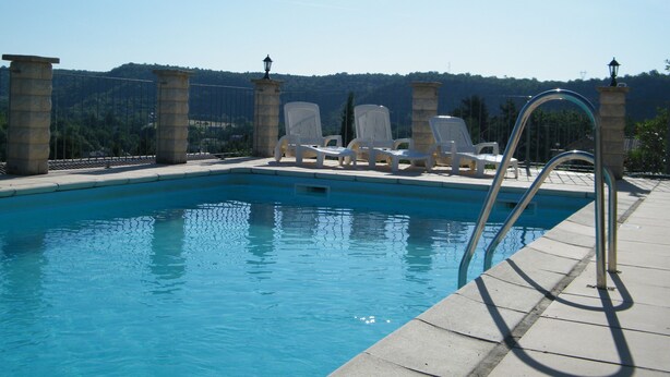 A swimming pool with a stone border, a metal ladder, and white lounge chairs. - Le Sapin B : Mooie Vakantiewoning met Zwembad in de Ardèche (Chassagnes)