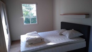 A bedroom with a bed, a window, and a shelf. - Le Sapin B : Mooie Vakantiewoning met Zwembad in de Ardèche (Chassagnes)