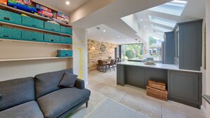 A modern kitchen with a skylight, a dining area with a brick wall, and a gray sofa. - Central Wimbledon House Sleeps 8 - Secluded Garden (London)