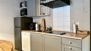 Cocina compacta con horno integrado, microondas y estufa a gas.