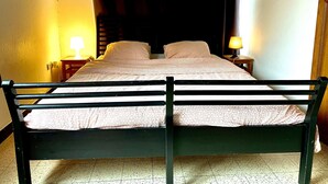 Una cama con cabecera, dos mesitas de noche con lámparas y suelo de baldosas.