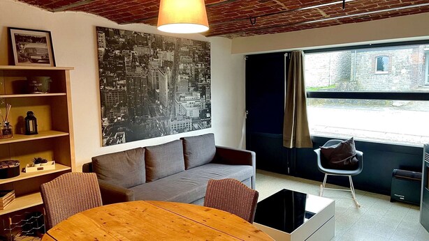 Una sala de estar moderna con un sofá gris, una mesa de centro de madera y un gran mural con un paisaje urbano en la pared.