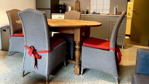 Una cocina compacta con comedor que incluye sillas de mimbre con cojines rojos y una mesa de madera.