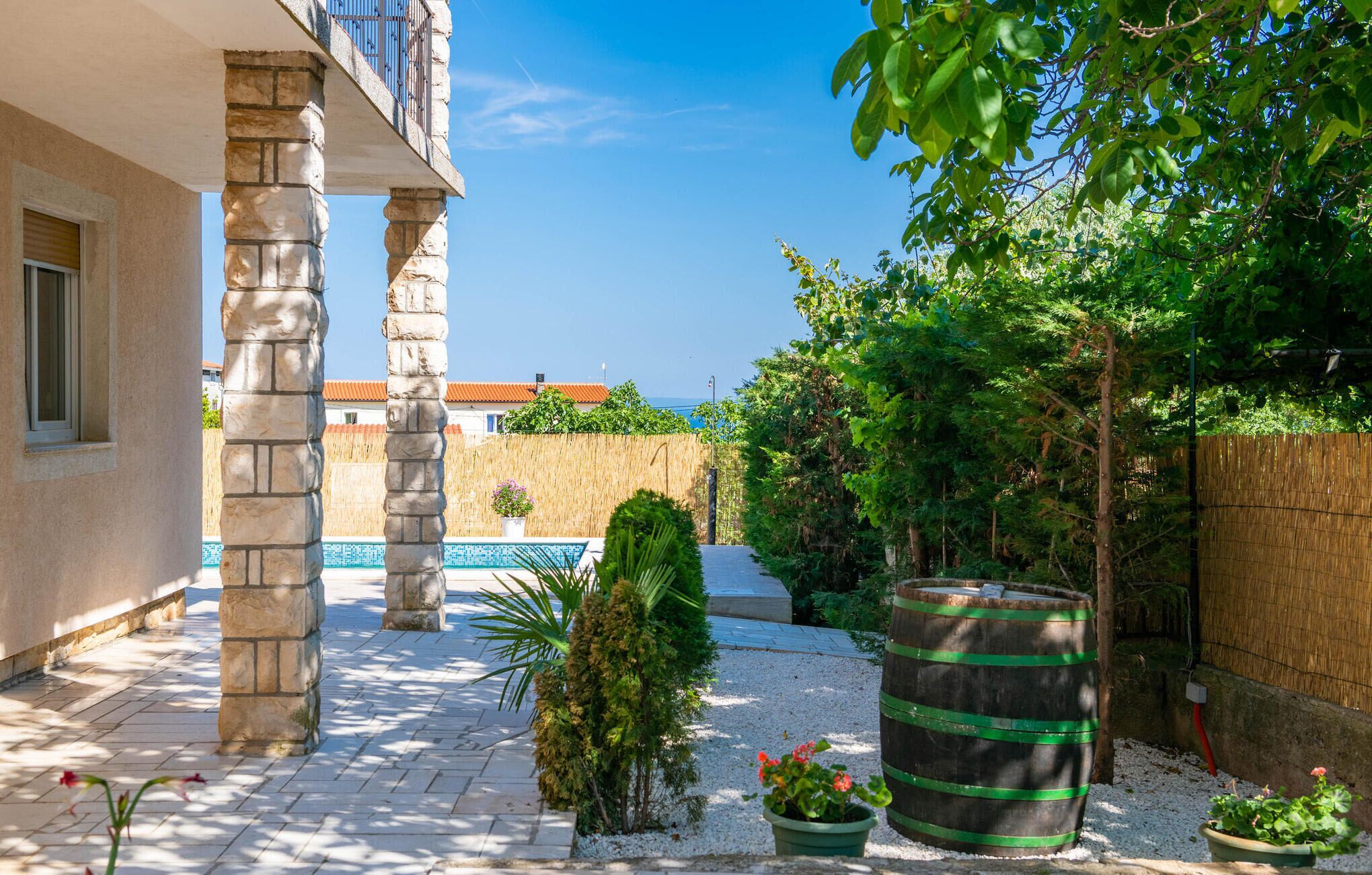 A courtyard with stone pillars, a swimming pool, and potted plants.