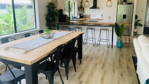A modern kitchen with a wooden table, black chairs, and a bar area with stools. - Modern country house set in the heart of the vines (McLaren Flat)