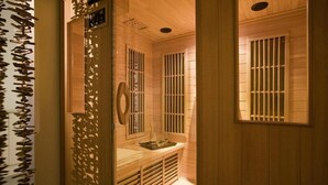 Un cuarto de sauna con paredes de madera, un banco y una ventana con barrotes.