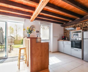Une cuisine dotée d’un îlot central en bois, d’un mur en pierre et offrant une vue sur l’extérieur.