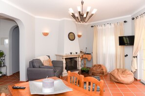 A living room with a fireplace, sofa, and television.