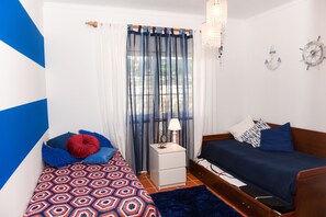 A bedroom with a bed, a nightstand, a dresser, and a window with curtains.