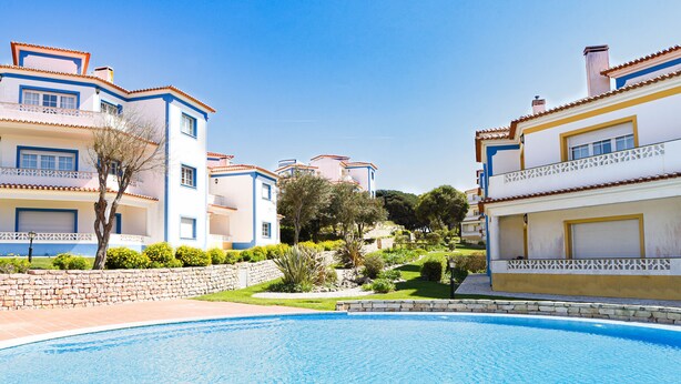 A swimming pool surrounded by multi-story buildings with balconies and a well-maintained garden. - The Quiet Loft Golf & Beach resort (Amoreira)