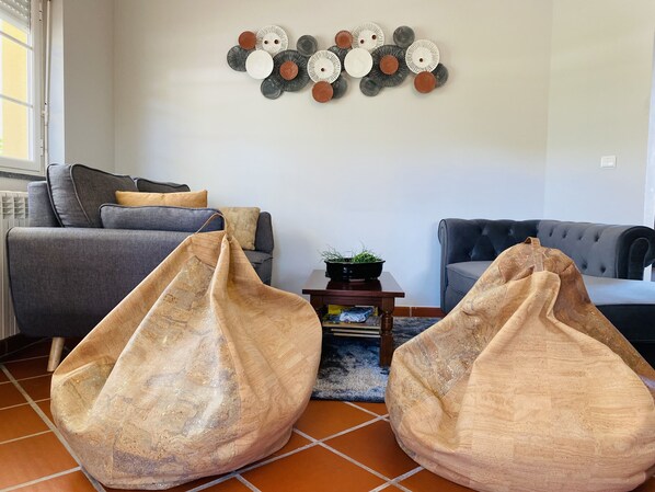 Un salon avec deux fauteuils poire, un canapé gris et un fauteuil gris.