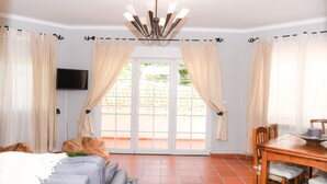 A room with a sofa, a dining table, and a TV on the wall. - The Quiet Loft Golf & Beach resort (Amoreira)